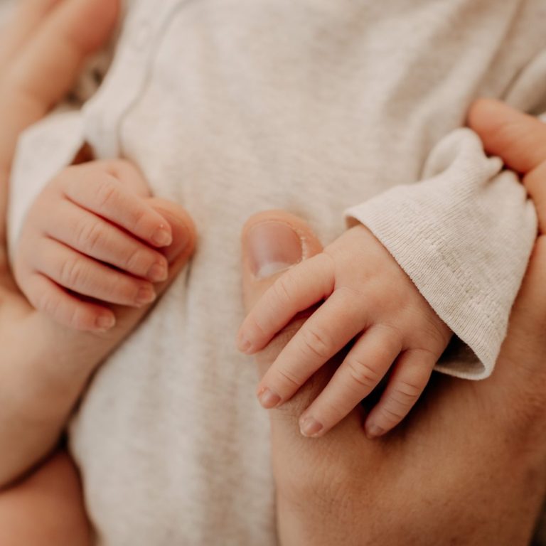  Babyhand greift schützend nach dem Finger eines Erwachsenen